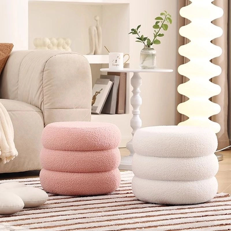 This sculptural pouffe ottoman, with its circular silhouette and tiered plush form, adds a unique dimension to contemporary living spaces