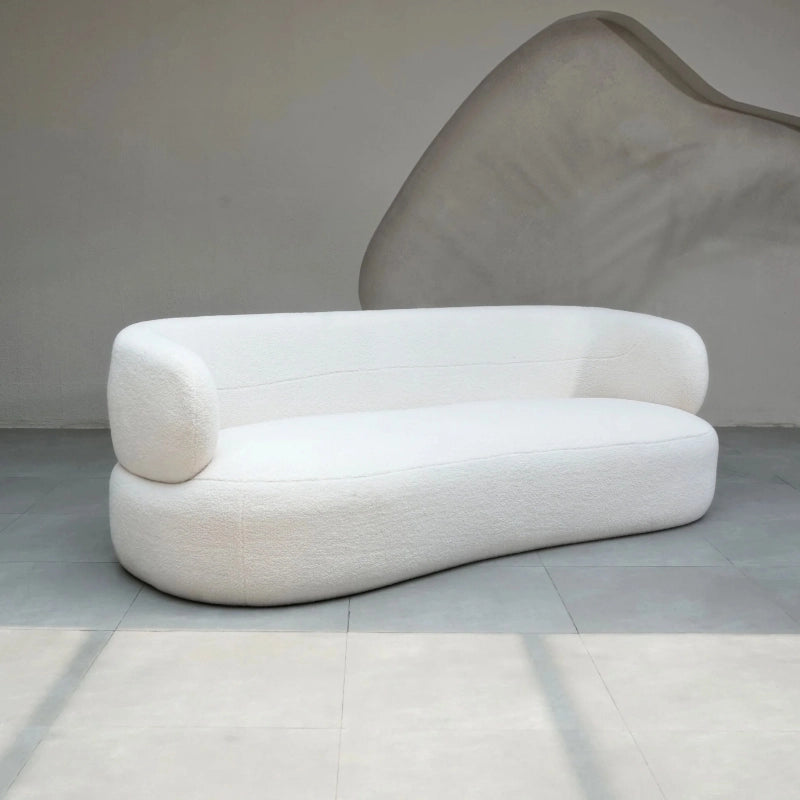 Shaped with smooth curves, it features fixed cushioning and a hidden base that lends a heavy visual anchor—ideal for grounded spaces like a living room or studio apartment.